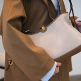 Close-up of a brown leather handbag with a beige interior.