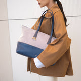 Woman holding a two-tone handbag against a neutral background