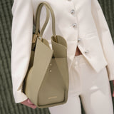 Person holding a green handbag with a white outfit against a textured green background
