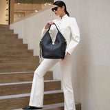 Woman in a white suit holding a black handbag on a staircase.