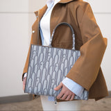 Woman holding a patterned handbag wearing a brown coat indoors.