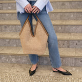 Person holding a woven handbag on stone steps