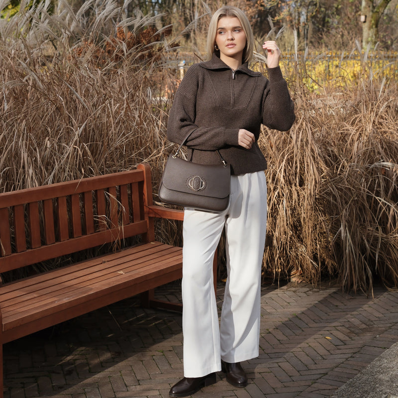 Woman standing in a park with dry grass and a bench in the background