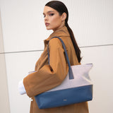 Woman holding a blue and white handbag against a neutral background