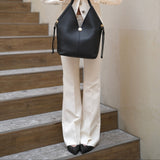 Woman in a white outfit holding a black handbag on a staircase